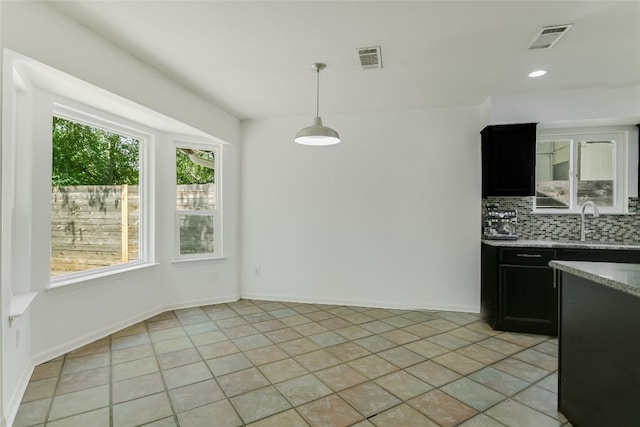 4015 Alexandria Dr, Austin, TX 78749 - kitchen with tasteful backsplash, dark cabinets, light stone counters, hanging light fixtures, and light tile patterned floors