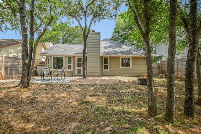 back of property with fence, a chimney, and a patio area