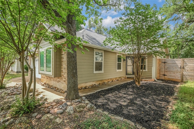 view of side of property featuring fence and roof with shingles