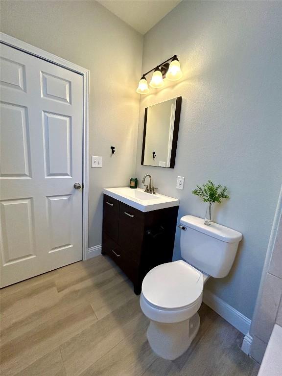 bathroom featuring baseboards, vanity, toilet, and wood finished floors