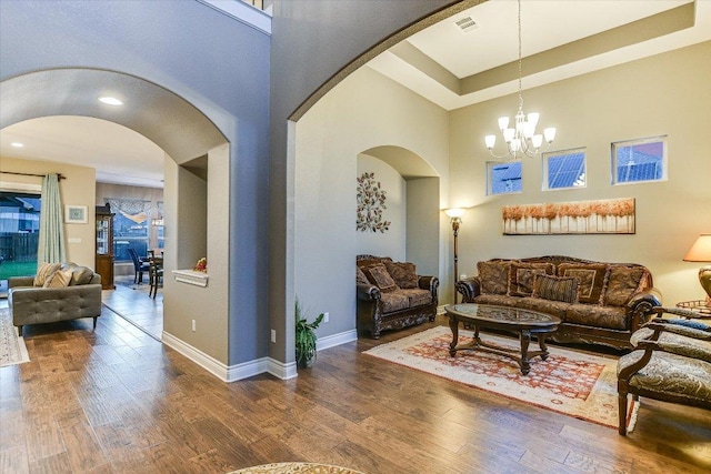 living room featuring arched walkways, wood finished floors, a chandelier, and baseboards