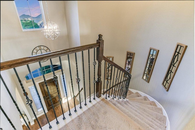 stairs featuring a chandelier, a towering ceiling, and baseboards