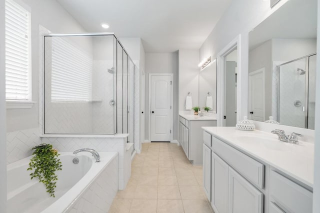 bathroom featuring a sink, tile patterned floors, two vanities, a bath, and a stall shower