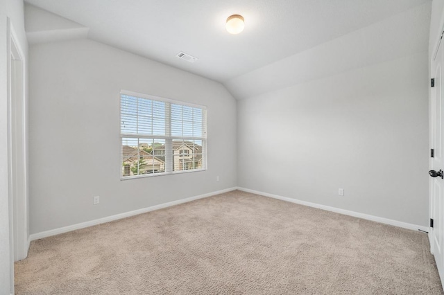 spare room featuring baseboards, carpet, vaulted ceiling, and visible vents