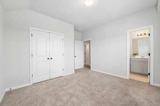 unfurnished bedroom with light carpet, a sink, ensuite bath, baseboards, and a closet