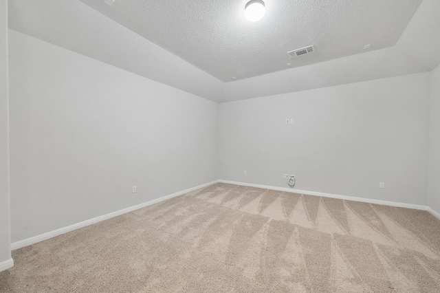 empty room with visible vents, baseboards, light colored carpet, a textured ceiling, and vaulted ceiling