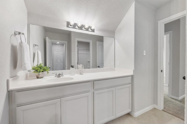 bathroom featuring vanity, a closet, baseboards, a textured ceiling, and tile patterned floors