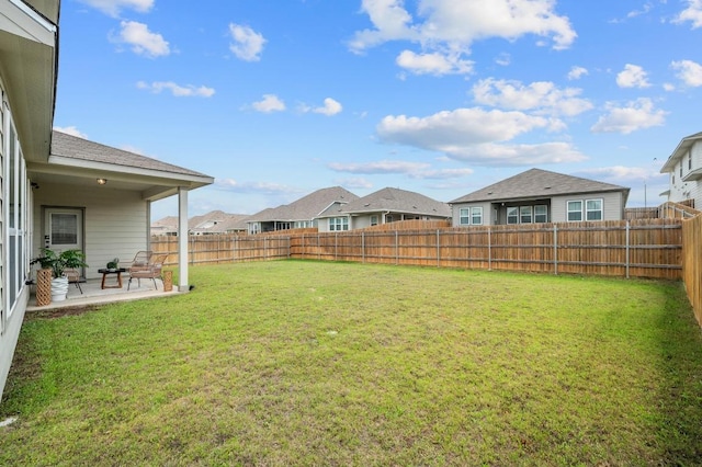 view of yard featuring a patio, a fenced backyard, and a residential view