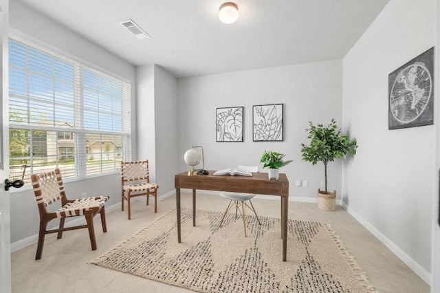 office space featuring baseboards, a wealth of natural light, and visible vents
