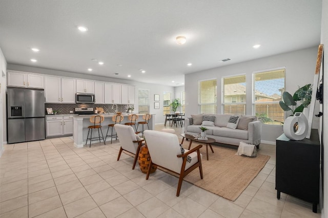 living area with light tile patterned floors, baseboards, recessed lighting, and visible vents