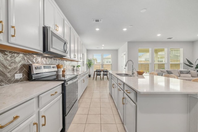 kitchen featuring backsplash, visible vents, a sink, light tile patterned floors, and stainless steel appliances