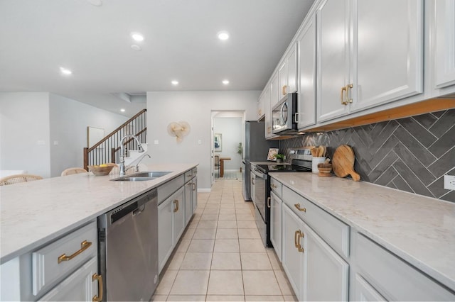 kitchen featuring appliances with stainless steel finishes, a sink, recessed lighting, decorative backsplash, and light tile patterned floors