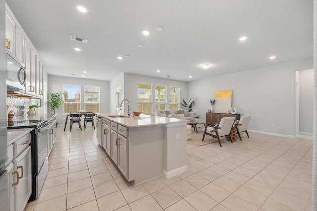 kitchen featuring stainless steel appliances, light tile patterned flooring, a healthy amount of sunlight, and a sink