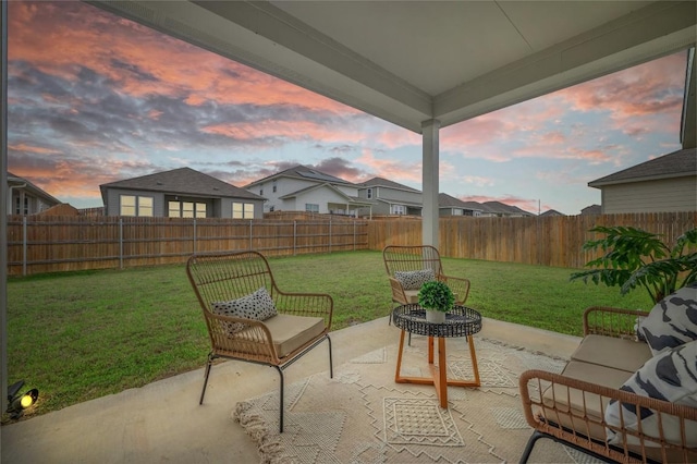 patio terrace at dusk featuring a lawn and a fenced backyard