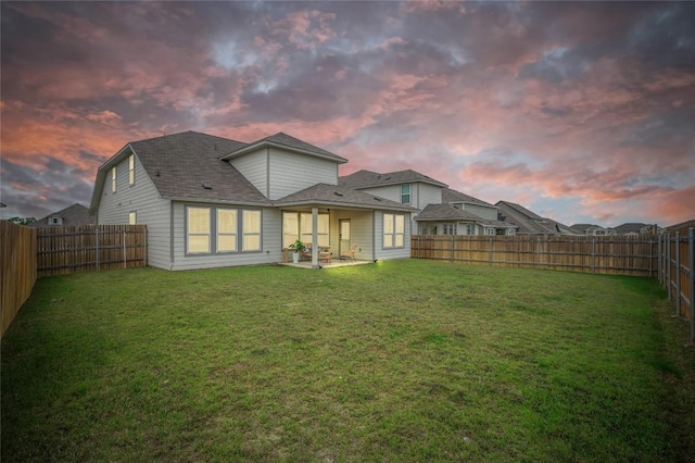 back of house with a fenced backyard, a lawn, and a patio area
