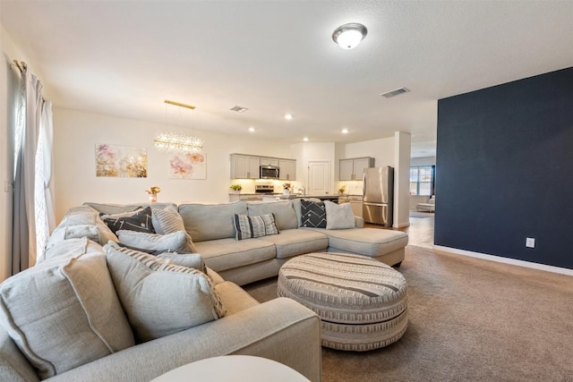 living room featuring light colored carpet, baseboards, visible vents, and a chandelier