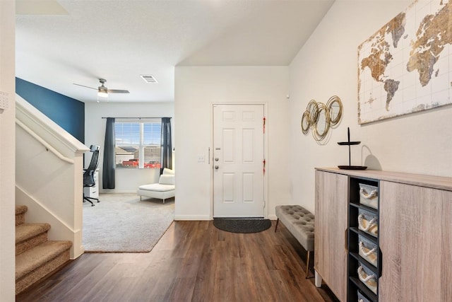 entrance foyer featuring visible vents, baseboards, stairway, dark wood-type flooring, and a ceiling fan