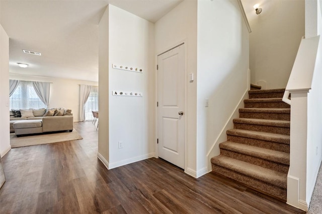 staircase featuring baseboards, wood finished floors, and visible vents