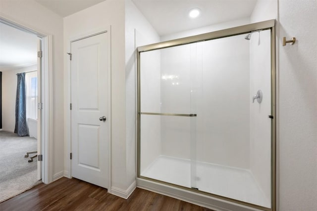 full bath with baseboards, wood finished floors, and a stall shower
