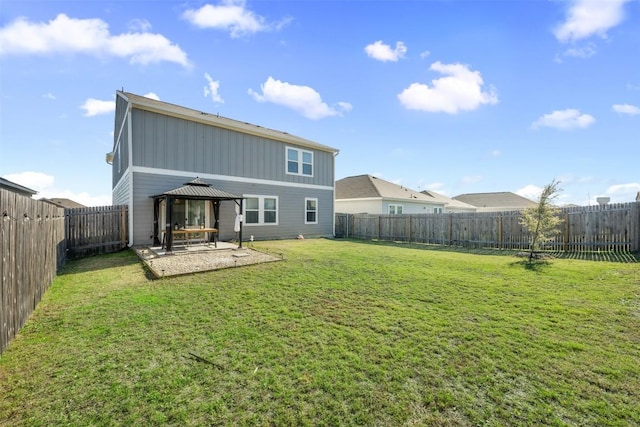 rear view of property featuring a gazebo, board and batten siding, a lawn, and a patio