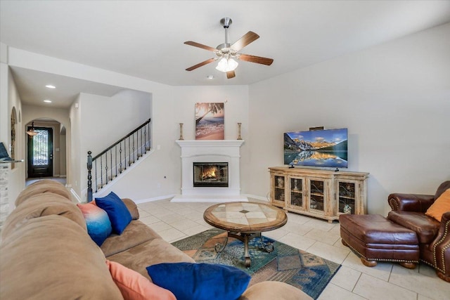 1901 Meandering Meadows Dr, Pflugerville, TX 78660 - tiled living room featuring a ceiling fan, arched walkways, stairs, a glass covered fireplace, and recessed lighting