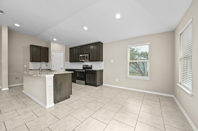 5407 Thunderbird St, Lago Vista, TX 78645 - kitchen with tasteful backsplash, light stone countertops, vaulted ceiling, a sink, and stainless steel appliances