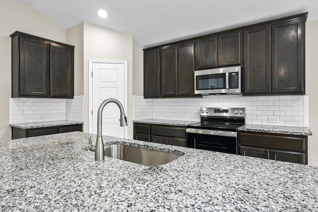 5407 Thunderbird St, Lago Vista, TX 78645 - kitchen featuring appliances with stainless steel finishes, a sink, light stone countertops, dark brown cabinetry, and tasteful backsplash