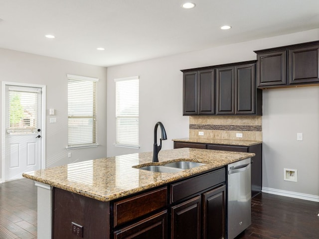 kitchen with dark wood-style flooring, dark brown cabinetry, a sink, dishwasher, and a center island with sink