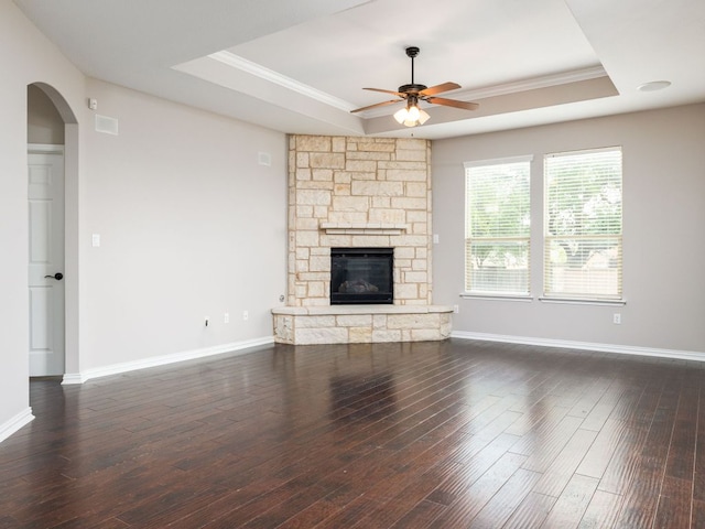 unfurnished living room with crown molding, a ceiling fan, a tray ceiling, and dark wood-style floors