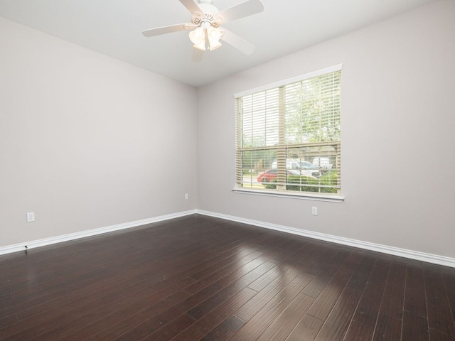 spare room with a ceiling fan, baseboards, and dark wood-type flooring