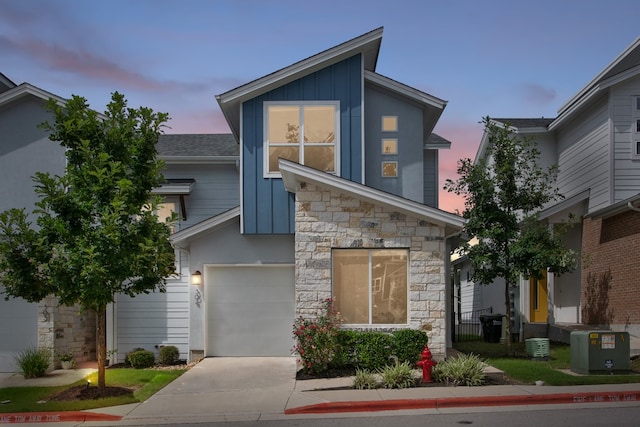 contemporary home with board and batten siding, concrete driveway, stone siding, and a garage