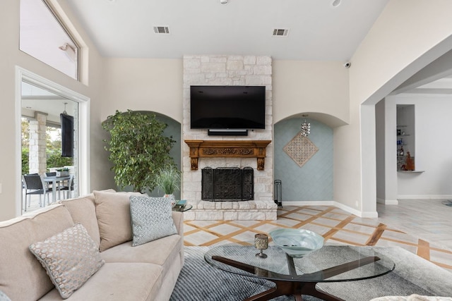 living area featuring baseboards, a stone fireplace, and visible vents