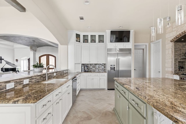 kitchen featuring visible vents, pendant lighting, appliances with stainless steel finishes, arched walkways, and a sink