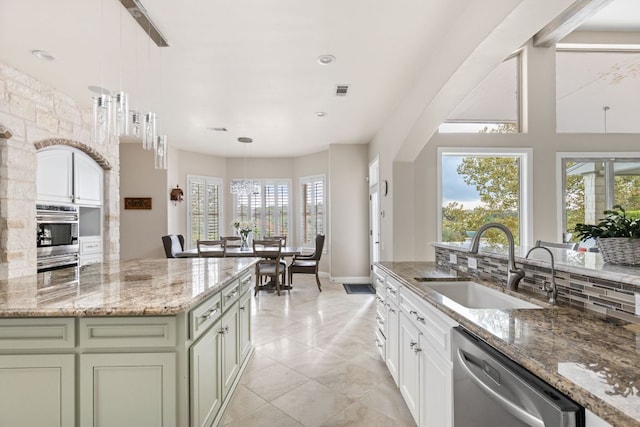kitchen featuring light stone countertops, appliances with stainless steel finishes, a sink, baseboards, and decorative backsplash