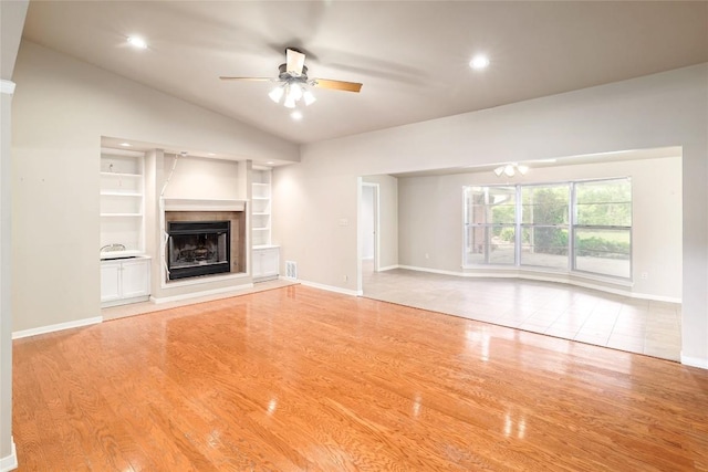 7300 Greenhaven Dr, Austin, TX 78757 - unfurnished living room with a ceiling fan, lofted ceiling, light wood-style flooring, a tile fireplace, and baseboards