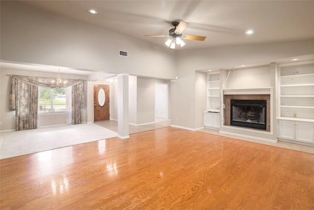7300 Greenhaven Dr, Austin, TX 78757 - unfurnished living room featuring a chandelier, baseboards, light wood-style flooring, ceiling fan, and a tiled fireplace