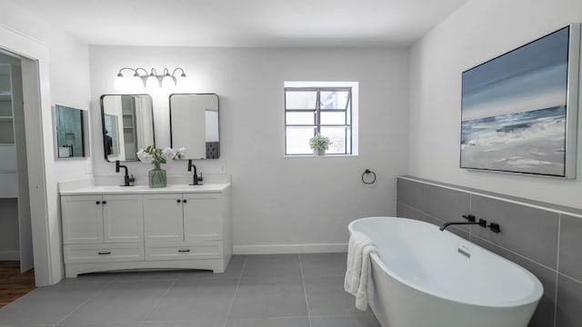 113 Augusta Dr, Wimberley, TX 78676 - full bathroom featuring double vanity, baseboards, a freestanding bath, tile patterned floors, and a sink