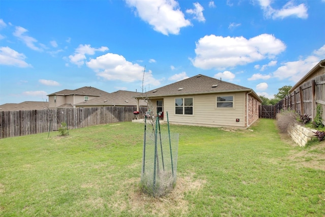 rear view of house featuring a lawn and a fenced backyard