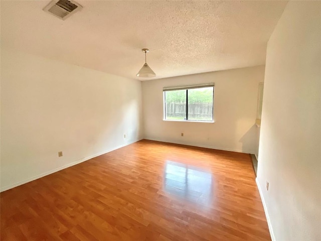 10810 Calcite Trl, Austin, TX 78750 - unfurnished room with visible vents, a textured ceiling, baseboards, and light wood-type flooring