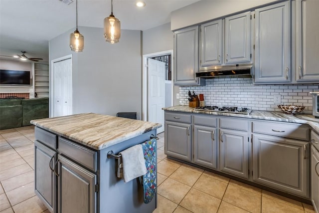 kitchen featuring stainless steel gas cooktop, a center island, a ceiling fan, under cabinet range hood, and gray cabinetry