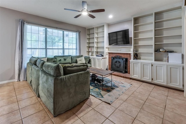 living room with a ceiling fan, built in features, a brick fireplace, baseboards, and light tile patterned flooring