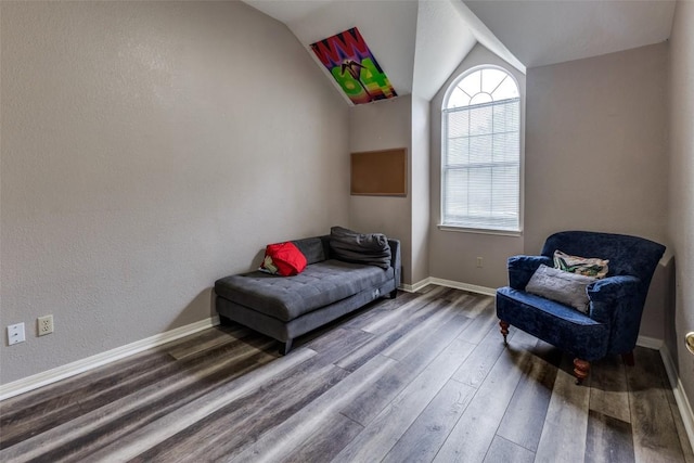 living area with baseboards, vaulted ceiling, a healthy amount of sunlight, and wood finished floors