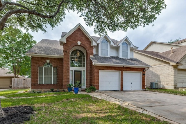 traditional home featuring roof with shingles, fence, a front lawn, brick siding, and driveway
