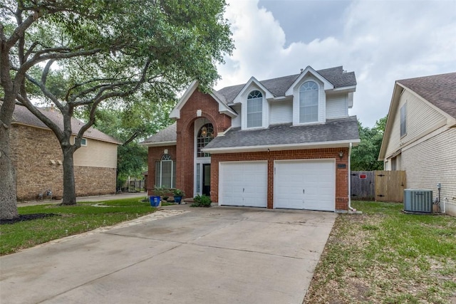 traditional-style house featuring central air condition unit, brick siding, fence, concrete driveway, and a shingled roof