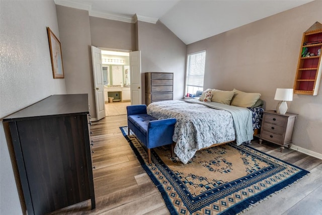 bedroom with crown molding, vaulted ceiling, wood finished floors, baseboards, and connected bathroom