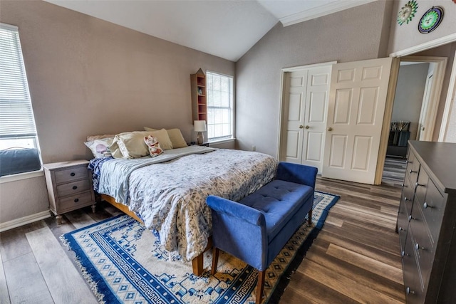 bedroom featuring crown molding, vaulted ceiling, dark wood finished floors, baseboards, and a closet