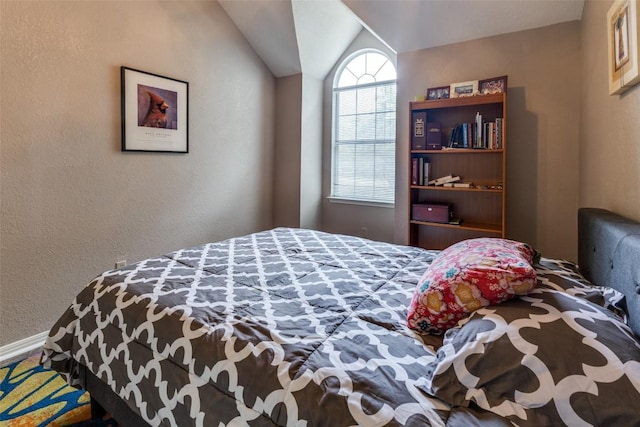 bedroom featuring a textured wall, baseboards, and lofted ceiling