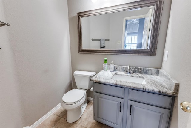half bathroom featuring tile patterned flooring, vanity, a textured wall, toilet, and baseboards