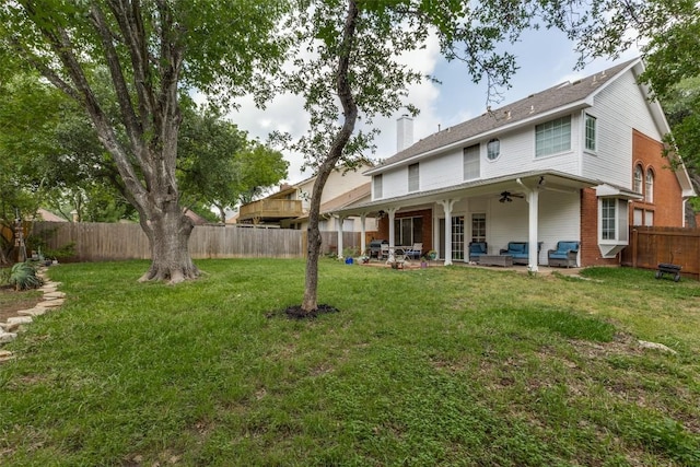rear view of house with an outdoor hangout area, a fenced backyard, a chimney, a patio area, and a yard