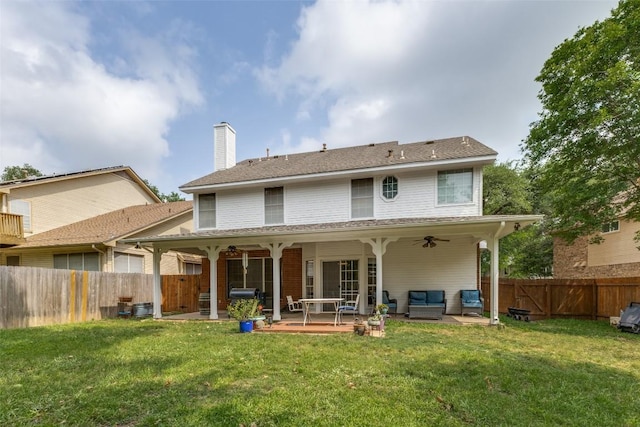 rear view of property featuring a lawn, a ceiling fan, a fenced backyard, and a chimney
